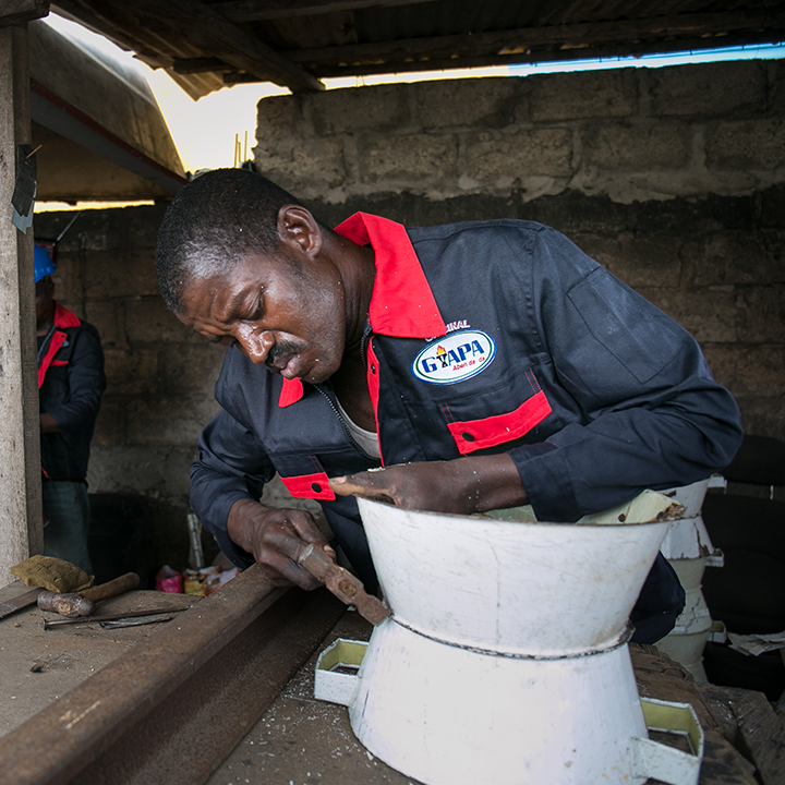 A metalworker prepares the shell of a Gyapa cookstove