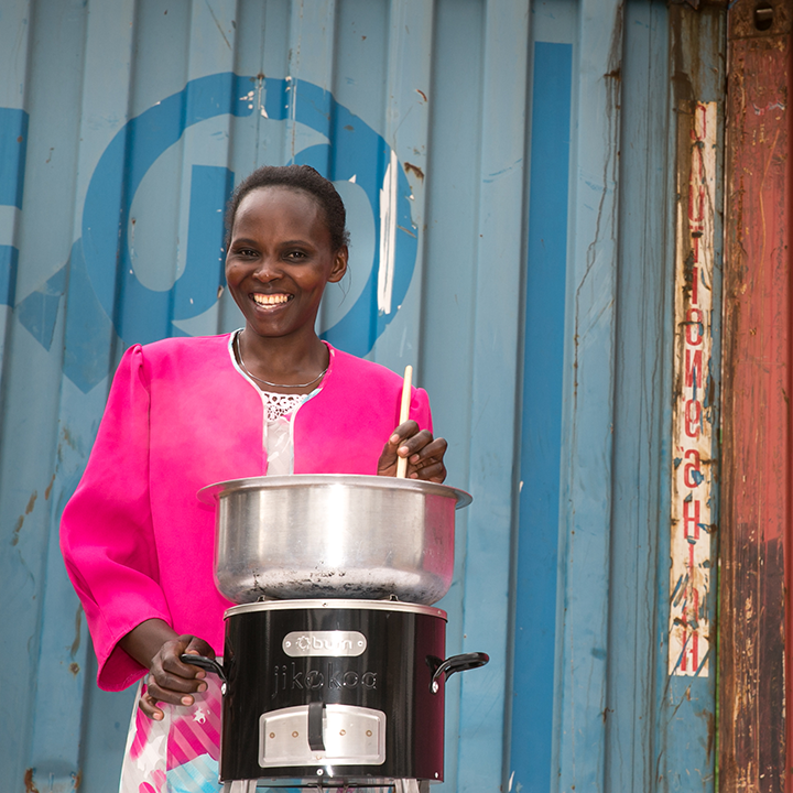 A woman cooks a meal on her fuel-efficient Burn Jikokoa stove